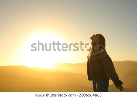 Side view portrait of a relaxed woman breathing fresh air at sunset in the mountain in winter