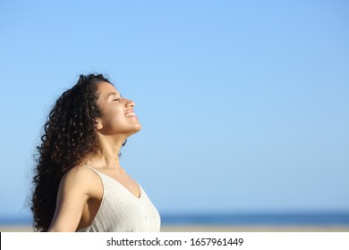 Side view portrait of a relaxed young woman breating and enjoying sun on the beach in summer