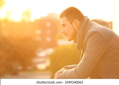 Side view portrait of a serious man looking away in a balcony at sunset in winter - Powered by Shutterstock