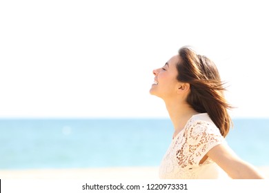 Side view portrait of a smiley lady breathing deep fresh air enjoying the wind on the beach - Powered by Shutterstock