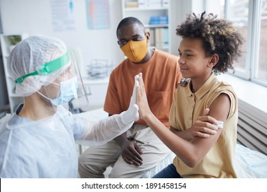 Side View Portrait Of Smiling African-American Boy High Five Nurse After Covid Vaccination In Clinic Or Hospital, Copy Space