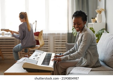 Side View Portrait Of Smiling Black Woman Playing Synthesizer At Home And Composing Music In Studio, Copy Space