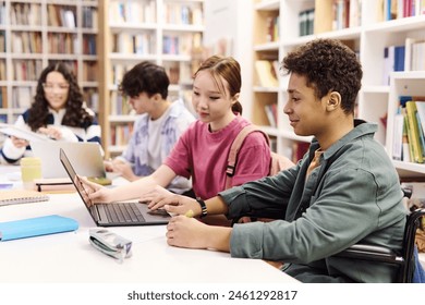 Side view portrait of smiling young boy using laptop in school library with diverse group of students copy space - Powered by Shutterstock