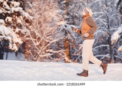 Side View Portrait Of Sporty Mature Woman Running In Winter Forest Lit By Sunset Light, Copy Space