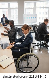 Side view portrait of successful businesswoman using wheelchair while working with computer in office, copy space