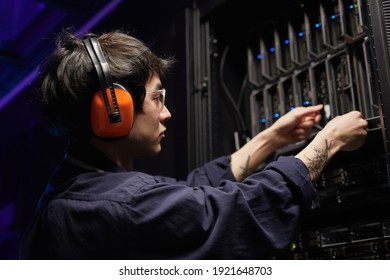 Seitenansicht des tätowierten jungen Netzwerkingenieurs, der Server im Rechenzentrum eines Supercomputers eingerichtet hat, Kopienraum