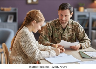 Side view portrait of teen girl studying at home with military father helping, copy space - Powered by Shutterstock