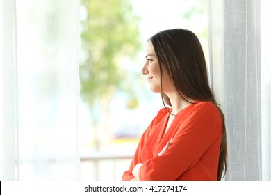 Side View Portrait Of A Thoughtful Attractive Female Looking The Green Background Outside Through A Window Of An Hotel Room Or Home