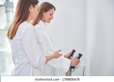 Side view portrait of two beautiful lady are exploring the parameters of body composition on the modern technology medicine machine - Powered by Shutterstock