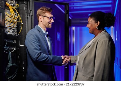 Side view portrait of two business partners shaking hands while standing in server room interior - Powered by Shutterstock