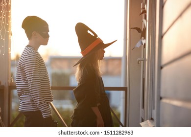 Side View Portrait Of Two Children Waiting By Door While Trick Or Treating On Halloween, Copy Space