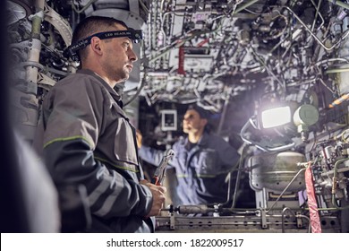 Side view portrait of two confident engineer working with electrical system of passenger aircraft