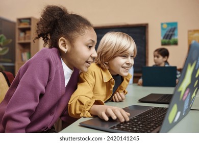 Side view portrait of two excited little kids looking at computer screen in school classroom copy space - Powered by Shutterstock