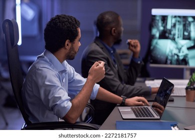 Side view portrait of two men looking at dgital board during meeting in IT security office