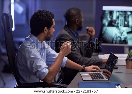 Side view portrait of two men looking at dgital board during meeting in IT security office