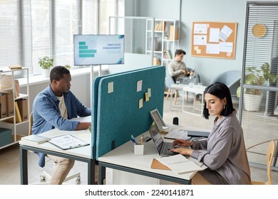 Side view portrait of two people working in office separated by partition wall