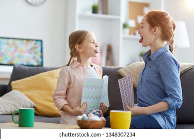 Side View Portrait Of Two Sisters Sticking Tongue Out While Teasing Each Other, Copy Space