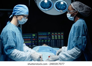 Side view portrait of two surgeons performing surgery in operating theater standing by patient copy space