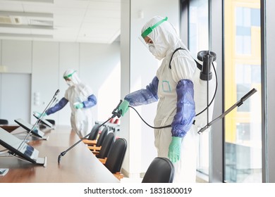 Side view portrait of two workers wearing hazmat suits disinfecting conference room in office, copy space - Powered by Shutterstock