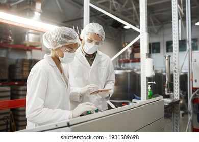 Side view portrait of two workers wearing protective clothing while operating machine units at chemical plant, copy space - Powered by Shutterstock