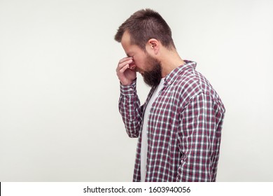 Side view portrait of unhappy bearded man in casual plaid shirt standing with head down, rubbing eyes and crying, tired depressed mood. empty place for text, copy space. isolated on white background - Powered by Shutterstock