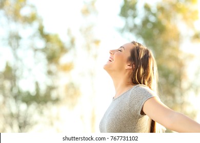 Side view portrait of a woman breathing fresh air outdoors in summer with trees and sky in the background - Shutterstock ID 767731102