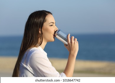 Side View Portrait Of A Woman Drinking Soda From A Can Outdoors On The Beach