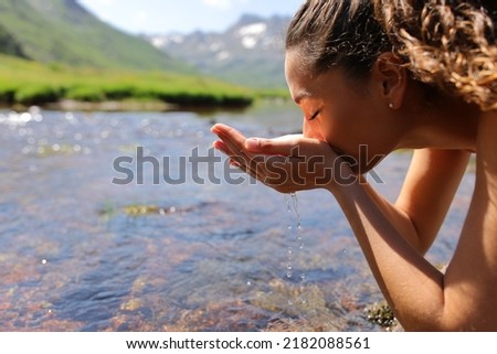 Side view portrait of a woman drinking raw water from river