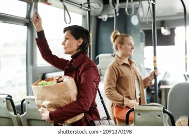 Side View Portrait Of Woman Holding Grocery Bag On Bus While Traveling By Public Transport And Holding Onto Railing, Copy Space