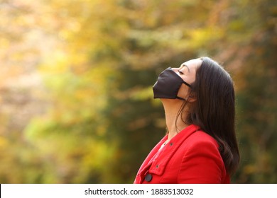 Side View Portrait Of A Woman In Red Breathing Fresh Air With Mask In A Forest In Covid Times