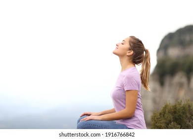 Side view portrait of a woman sitting breathing fresh air in the mountain