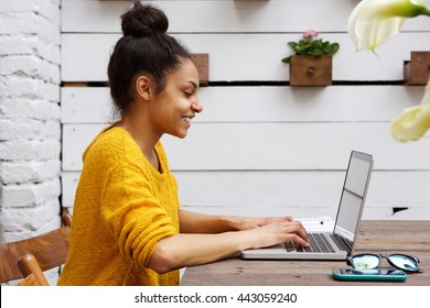 Side View Portrait Of Young African American Woman Working On Laptop At Cafe