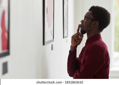 Side View Portrait Of Young African-American Man Looking At Paintings And Thinking At Art Gallery Or Museum Exhibition, Copy Space