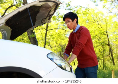 Side View Portrait Of A Young Asian Man Checking His Car Engine