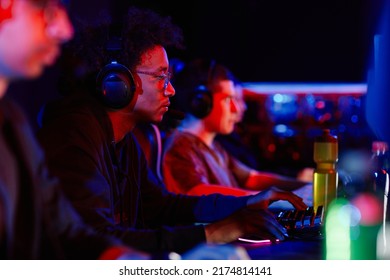 Side View Portrait Of Young Black Man Playing Video Games With Cyber Sports Team In Neon Light