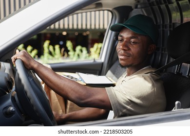 Side View Portrait Of Young Black Man Driving Delivery Truck And Wearing Uniform