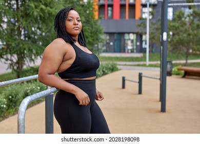 Side View Portrait Of Young Fat Plus Size Woman In Sportive Outfit Posing Outdoors After Sport Workout, Have Rest, Taking A Break During Exercises, Looking At Camera Confidently. Copy Space, Sport - Powered by Shutterstock