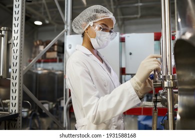 Side View Portrait Of Young Female Worker Wearing Protective Clothing While Operating Equipment At Chemical Plant, Copy Space