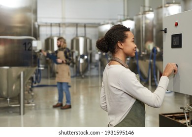 Side view portrait of young female worker operating machines in brewery workshop, copy space - Powered by Shutterstock