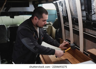 Side View Portrait Of Young Man Building Camper Van And Installing Furniture In Kitchen Area