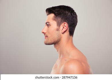 Side View Portrait Of A Young Man With Nude Torso Over Gray Background