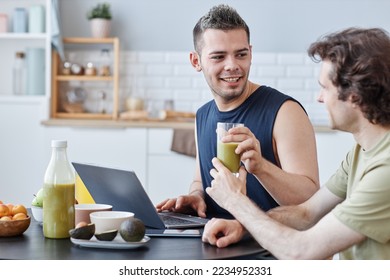 Side view portrait of young same sex couple enjoying breakfast together in morning and sharing healthy smoothie
