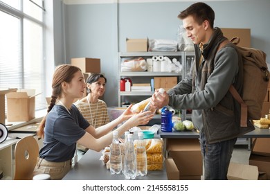 Side view portrait of young woman giving out donations while volunteering at help center for refugees - Shutterstock ID 2145558155