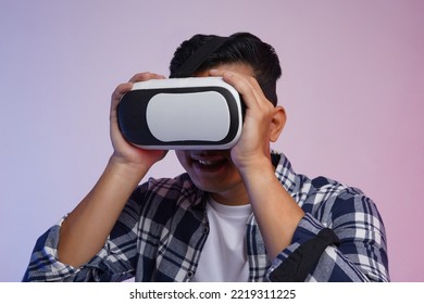 Side View. Potrait Of Young Asian Man Excited Wearing Casual Shirt And Virtual Reality Headset Or VR Glasses, Playing Video Game, Isolated On White Background