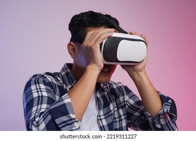 Side View. Potrait Of Young Asian Man Excited Wearing Casual Shirt And Virtual Reality Headset Or VR Glasses, Playing Video Game, Isolated On White Background