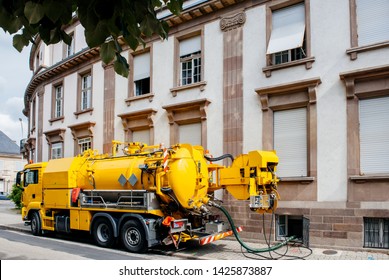Side view of powerful professional modern yellow sewage sewerage truck working near a house pumping basement canalisation water