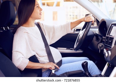 Side View Of Pregnant Woman On Driver Seat Adjusts Seat Belt