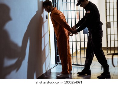 Side View Of Prison Officer Wearing Handcuffs On Prisoner