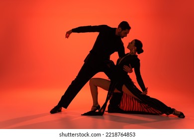 Side view of professional dancer hugging woman in dress on red background 