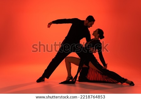 Side view of professional dancer hugging woman in dress on red background 